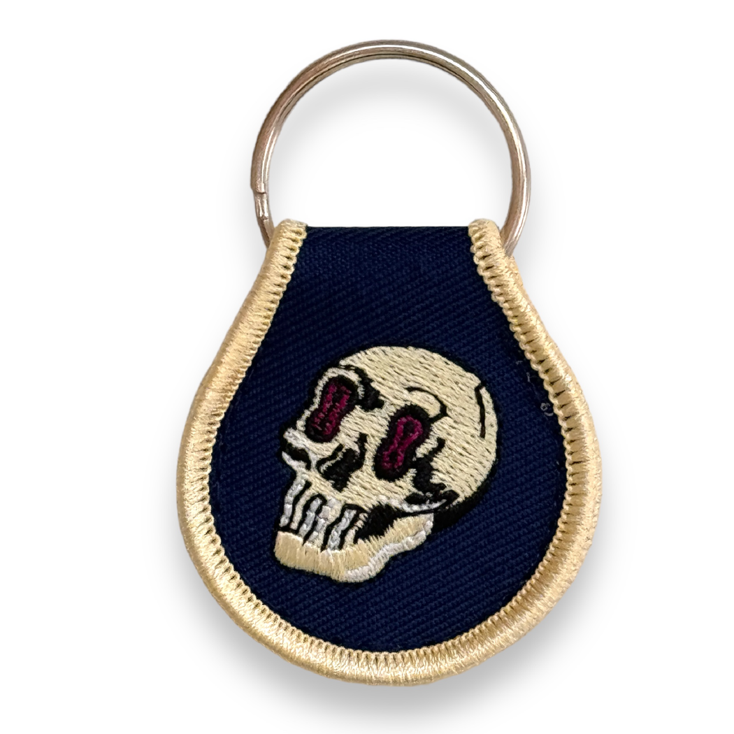 Distinctive keychain embroidered with gold border and unique Puppyteeth gold skull. Double-sided, attached to ring.