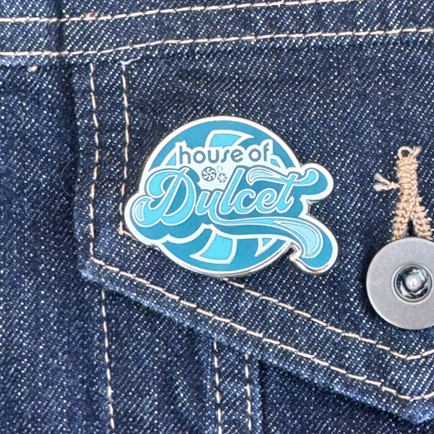 Blue and white House of Dulcet logo pin.