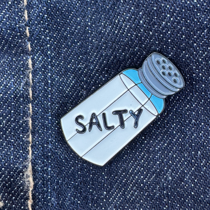 Salt shaker shaped lapel pin with the word Salty written on it.