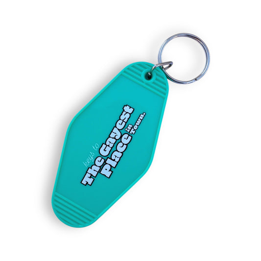 Turquoise vintage-shaped motel keychain with the words: Keys to the Gayest Place in Town.