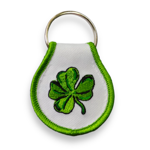 White droplet-shaped keychain embroidered with green border and green four-leaf shamrock.